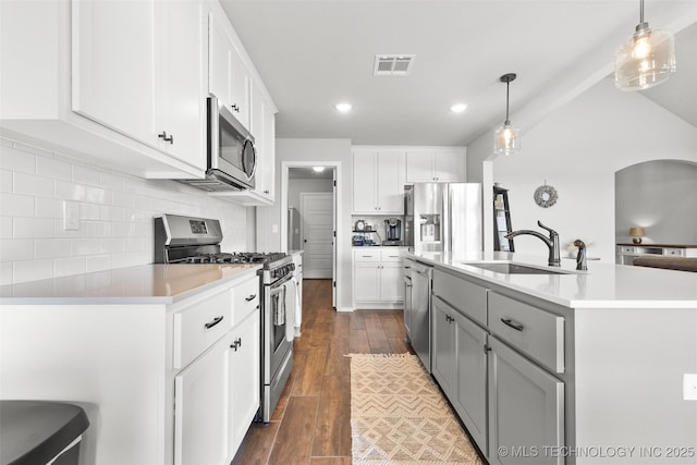 kitchen featuring visible vents, dark wood-style floors, stainless steel appliances, light countertops, and a sink