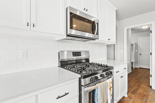 kitchen with stainless steel appliances, dark wood-type flooring, white cabinetry, light countertops, and decorative backsplash