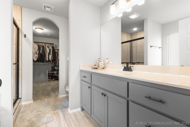 full bath featuring visible vents, a spacious closet, toilet, a shower stall, and vanity