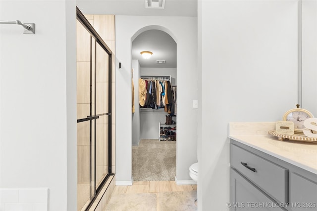 bathroom with a stall shower, visible vents, a spacious closet, and toilet