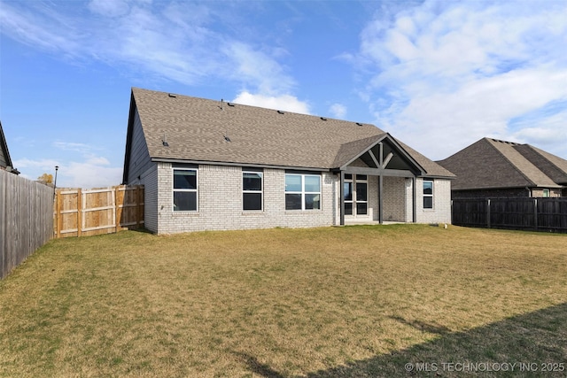 back of property featuring a fenced backyard, a shingled roof, a lawn, and brick siding