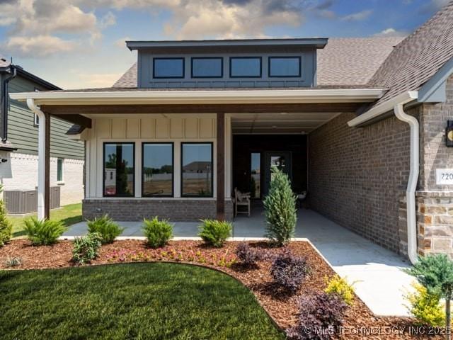 property entrance featuring a yard, board and batten siding, and brick siding