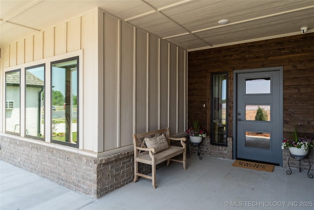 view of exterior entry featuring board and batten siding and brick siding