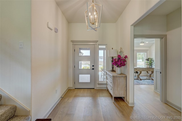 entrance foyer with a notable chandelier, light wood-style flooring, baseboards, and stairs