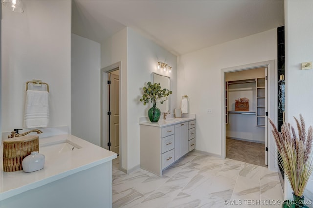 full bathroom featuring a sink, two vanities, baseboards, marble finish floor, and a spacious closet