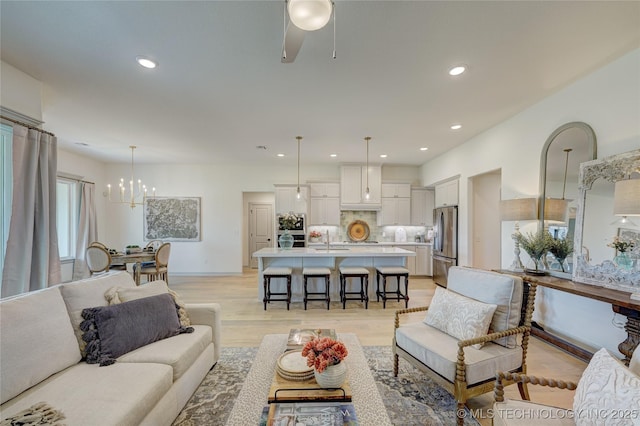 living area featuring light wood-style flooring, baseboards, a chandelier, and recessed lighting