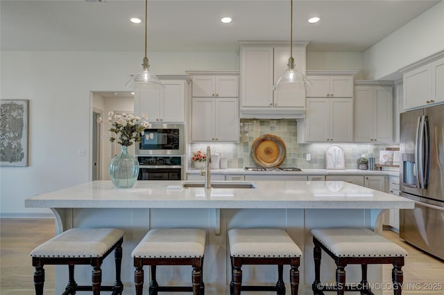 kitchen featuring decorative backsplash, light wood-style flooring, appliances with stainless steel finishes, light countertops, and a sink