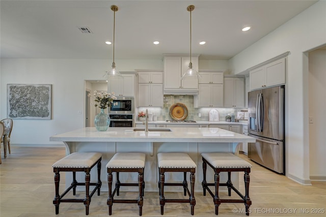 kitchen featuring a sink, visible vents, light countertops, appliances with stainless steel finishes, and decorative backsplash