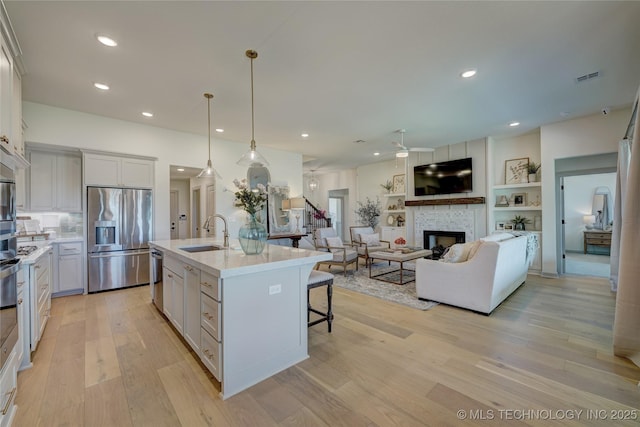 kitchen with a large fireplace, appliances with stainless steel finishes, light countertops, and a sink