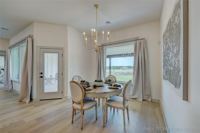 dining area with light wood finished floors, baseboards, visible vents, and an inviting chandelier