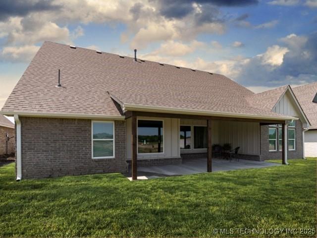 rear view of house featuring a patio, brick siding, a lawn, and a shingled roof