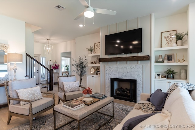 living area with visible vents, built in features, wood finished floors, stairs, and a fireplace