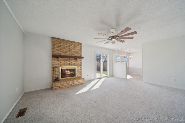 unfurnished living room with ceiling fan with notable chandelier, a fireplace, carpet flooring, and visible vents