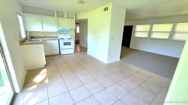 kitchen featuring light carpet, electric range, visible vents, a sink, and light tile patterned flooring