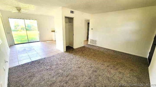 carpeted spare room with visible vents, ceiling fan, and a textured ceiling