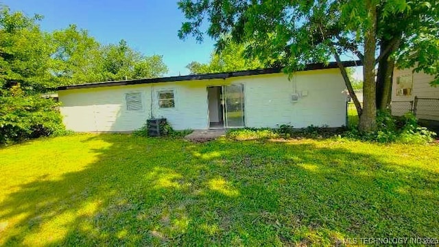 rear view of house with a lawn and central AC unit