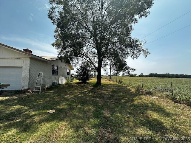 view of yard with an attached garage and fence