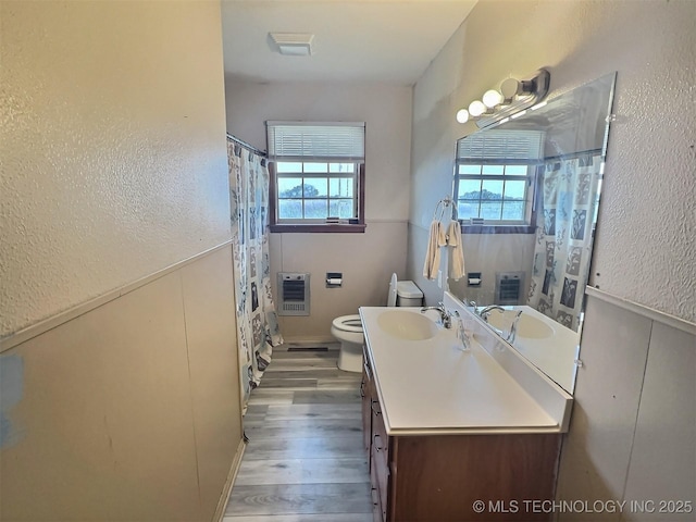 bathroom with toilet, a shower with shower curtain, wood finished floors, vanity, and heating unit