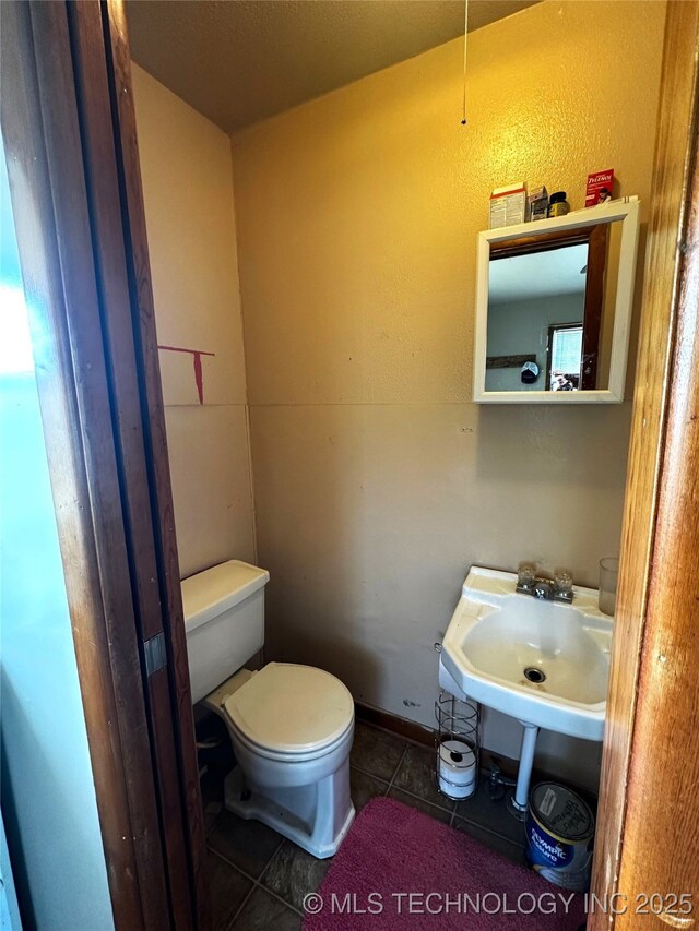 bathroom featuring a sink, toilet, and tile patterned floors