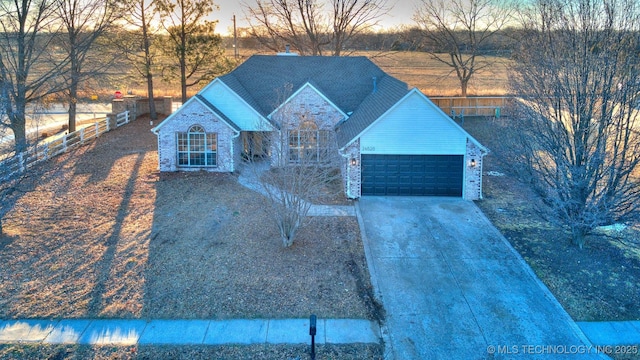 view of front of property with brick siding, fence, driveway, and an attached garage