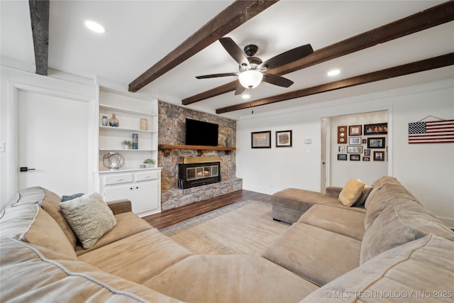 living area featuring ceiling fan, recessed lighting, a fireplace, wood finished floors, and beam ceiling