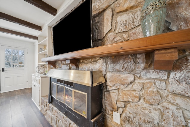 interior details featuring wood finished floors, a glass covered fireplace, and beam ceiling