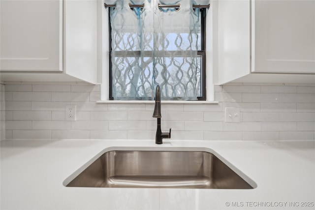 details with decorative backsplash, white cabinets, a sink, and light countertops