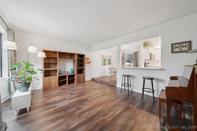 living area with dark wood-type flooring and baseboards