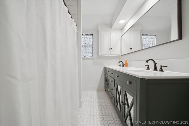 full bath featuring double vanity, recessed lighting, a sink, and baseboards