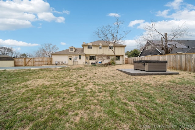 rear view of house featuring a yard, a hot tub, a fenced backyard, and a patio