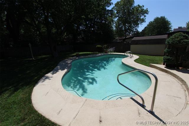 outdoor pool with an outbuilding, a fenced backyard, and a shed