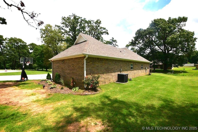 view of property exterior featuring brick siding, a yard, central AC, and roof with shingles