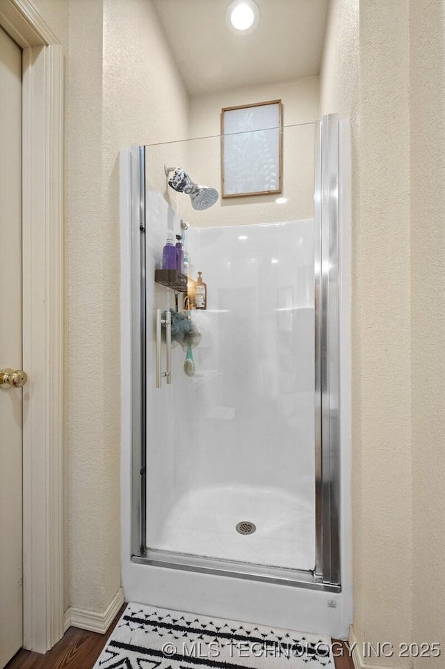 full bathroom featuring a stall shower and a textured wall