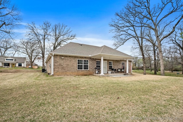 rear view of property with a yard, a patio, brick siding, and a shingled roof