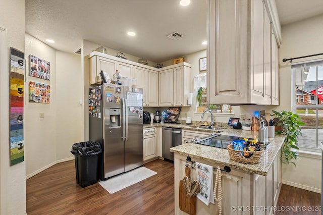 kitchen with visible vents, dark wood finished floors, appliances with stainless steel finishes, light stone countertops, and a sink