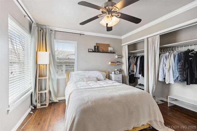 bedroom with a ceiling fan, crown molding, baseboards, and wood finished floors