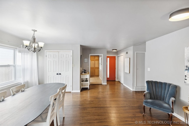 dining space featuring dark wood finished floors, an inviting chandelier, and baseboards