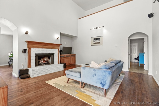 living area with arched walkways, wood finished floors, and a fireplace