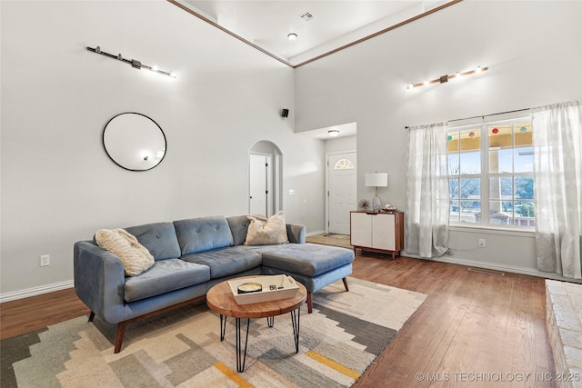 living area featuring wood finished floors, visible vents, arched walkways, and baseboards