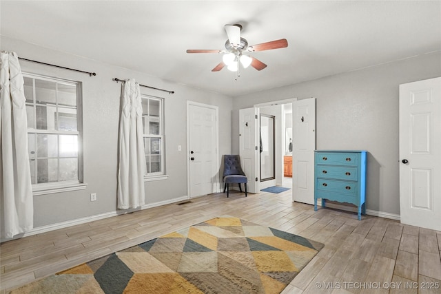 unfurnished room featuring baseboards, light wood-type flooring, and ceiling fan