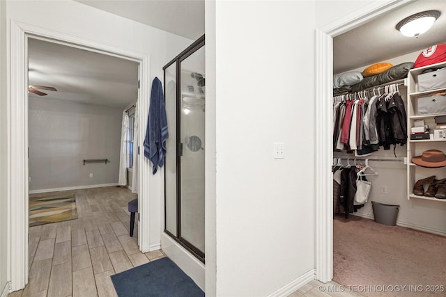 full bathroom featuring a walk in closet, wood finished floors, and a stall shower