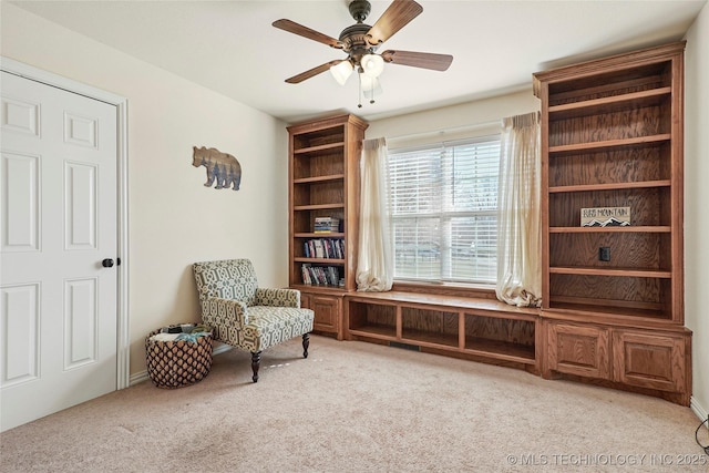 living area featuring a ceiling fan and carpet