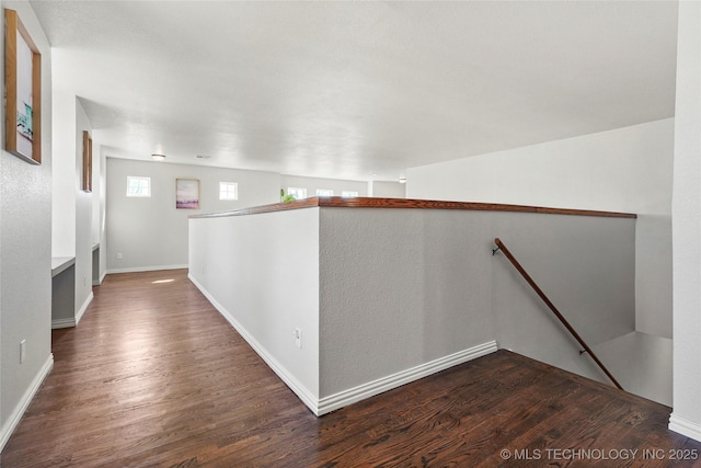 hallway with dark wood finished floors, an upstairs landing, and baseboards