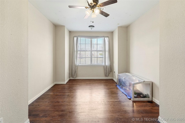 spare room featuring a textured wall, baseboards, ceiling fan, and wood finished floors