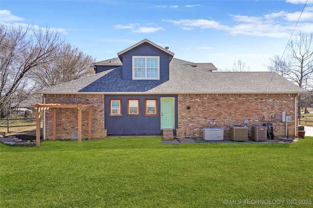 back of house featuring a yard, brick siding, and a shingled roof