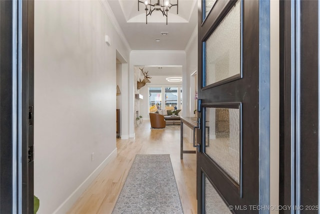 entrance foyer featuring baseboards, ornamental molding, a notable chandelier, and light wood-style floors