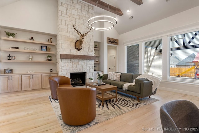 living room with light wood-style flooring, a fireplace, high vaulted ceiling, and baseboards