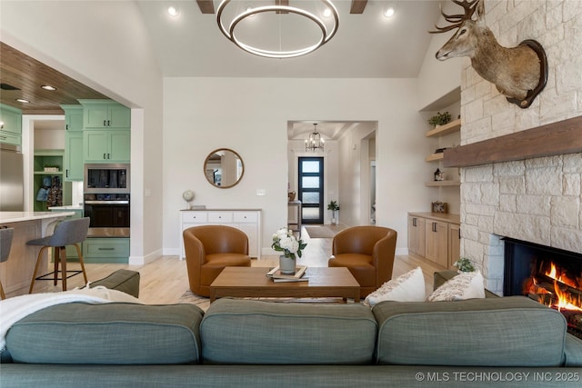 living room featuring light wood finished floors, baseboards, a fireplace, high vaulted ceiling, and recessed lighting