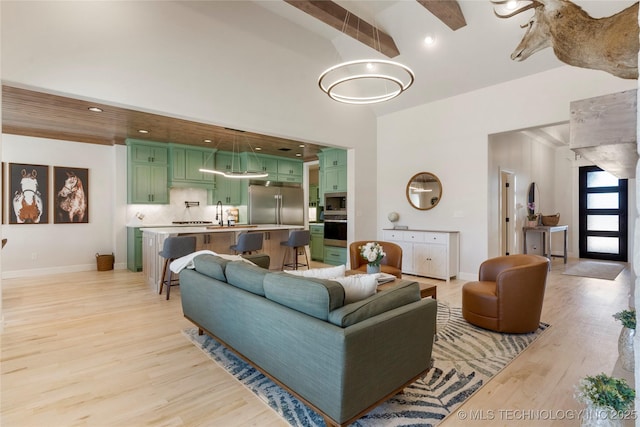 living area with high vaulted ceiling, light wood finished floors, recessed lighting, and baseboards