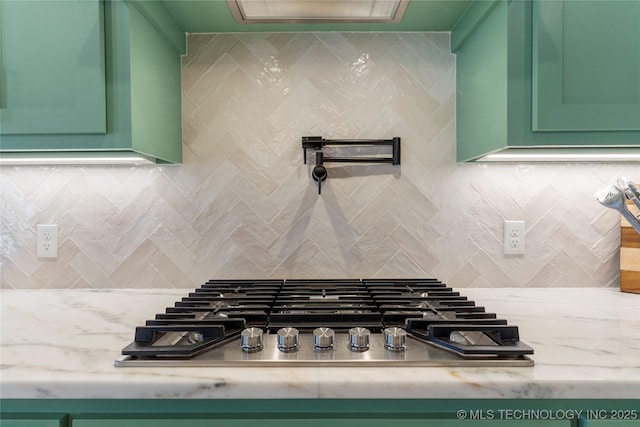 room details featuring stainless steel gas cooktop, backsplash, and green cabinets